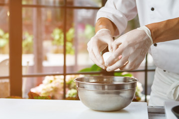 Man's hand holding an egg. White chicken egg. Chef starts preparing omelet. Only clean products.