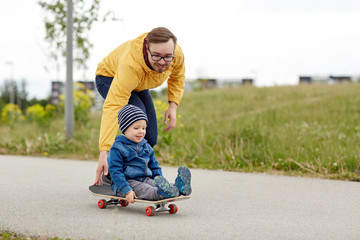 Obraz premium happy father and little son riding on skateboard