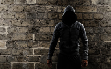 Fototapeta na wymiar Mann mit einem Hoodie vor einer Mauer