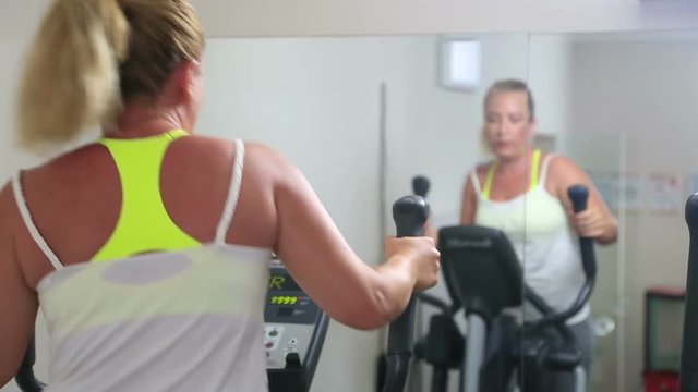 Woman trains on stepper machine in gym. Concept of health and fitness.