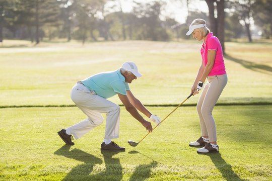 Mature male teaching woman to play golf