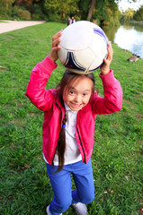 Cute little girl paying in the park with a ball.