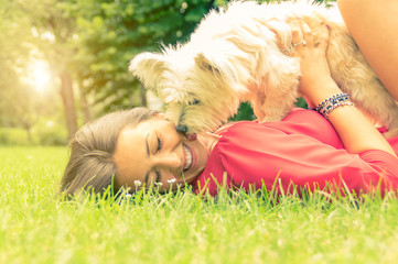 White dog kissing it's owner lying on the grass