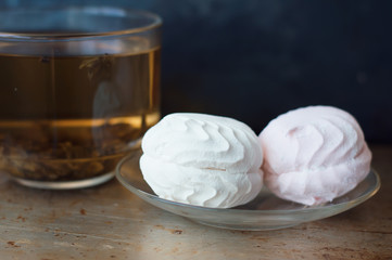 Two pieces of zephyr dessert on a small glass plate and cup of green tea