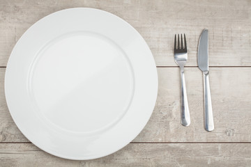 Empty Plate, Fork, Knife on wooden background. Top View with Text Space