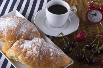 Image of alarm clock, hot coffee and croissants.