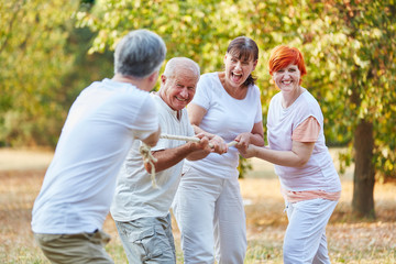 Gruppe Senioren beim Tauziehen im Park