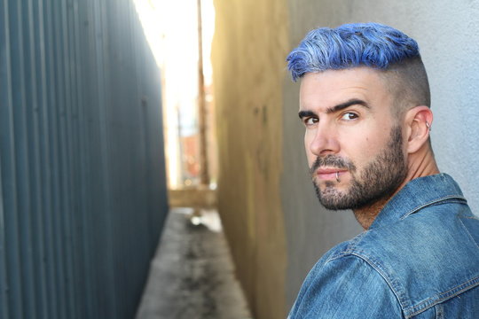 Head shot of handsome blue haired young man outdoors looking in camera