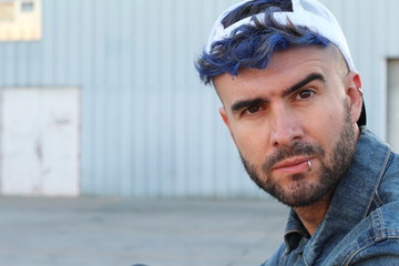 Drug addicted young rebel man with blue died hair sitting on suspicious dark alley way with copy space 