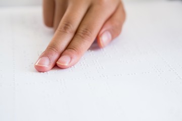 Cropped image of child hand reading braille book
