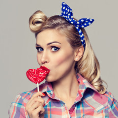 woman eating heart shape lollipop, dressed in pin-up style