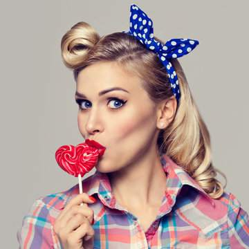 woman eating heart shape lollipop, dressed in pin-up style
