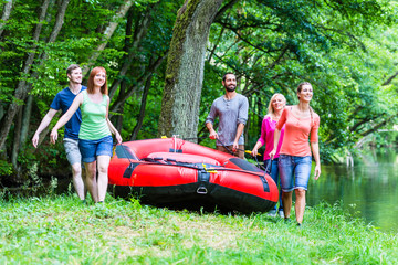 Freunde tragen Schlauchboot zum Wald Fluss 