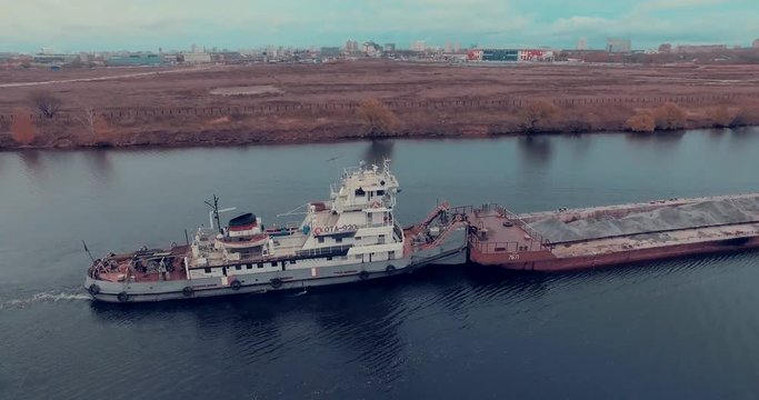 Aerial view of  barge transporting gravel down Moskva River on a cloudy autumn day in Strogino district, Moscow, Russia.  