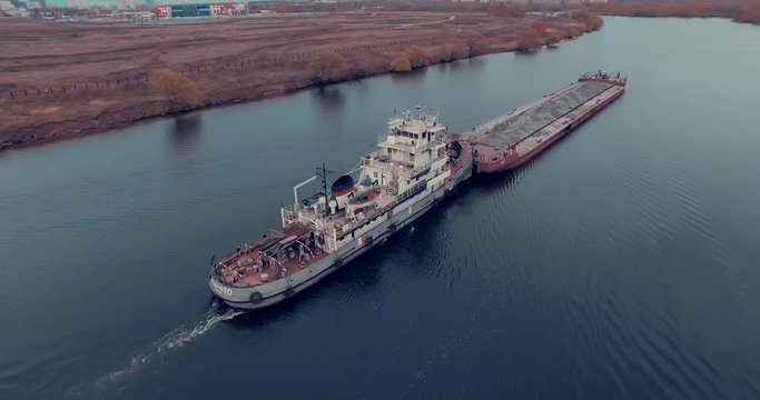 Aerial view of  barge transporting gravel down Moskva River on a cloudy autumn day in Strogino district, Moscow, Russia.  