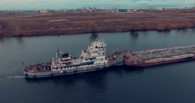 Aerial view of  barge transporting gravel down Moskva River on a cloudy autumn day in Strogino district, Moscow, Russia.  