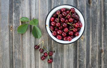 Cherries in bowl on rustic grunge wooden background top view.