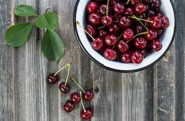 Fresh cherries in bowl on rustic grunge wooden background top view