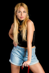 a sexy girl with long blond hair in blue shorts standing in the black background for advertising. The background can be changed