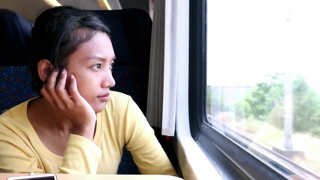 Young woman takes the train. Passengers traveling on the train looking out the window at the passing landscape.
