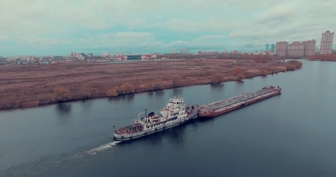Aerial view of  barge transporting gravel down Moskva River on a cloudy autumn day in Strogino district, Moscow, Russia.  