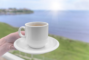 Cup in hand on background of the sea.