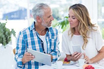 Man showing digital tablet to woman in restaurant