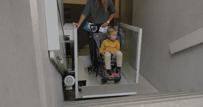Mother and son in baby carriage using special transporter to get upstairs