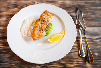 Grilled Fish with slice of lemon and white sause on wooden backg