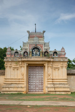 Chettinad, India - October 18, 2013: Entrance to Nagar Soorakudi Sundesaswar Meenakshi Ambal Temple. Yellow wall and gate decorated with statues.