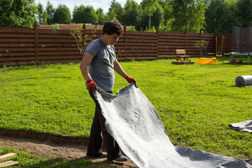 man lay geotextiles in pit for garden path