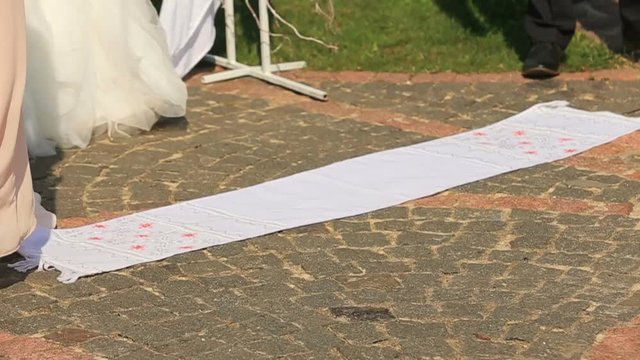 Wedding ceremony outdors. Newlyweds stands on the traditional rushnyk