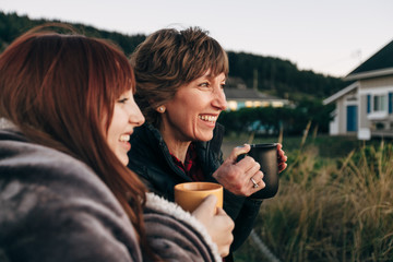 Mother and Daughter Drinking from Coffee Cups at Sunset