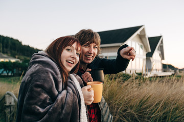 Mother and Daughter Drinking from Coffee Cups at Sunset