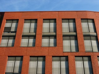Heruntergelassene Jalousie als Schutz vor der Sonne am Fenster eines modernen Bürohaus mit...