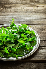 Silver tray with mint leaves on a old wooden table.