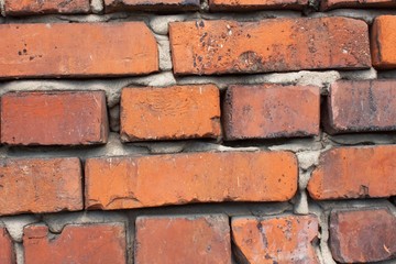 Fototapeta premium Old wall from red brick. Red clay brick. Brick wall. The old crumbling brick wall. Bricks and stones in the old wall. The old brick wall collapses and urgent repair is necessary. 