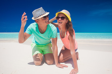 Couple in bright clothes and hats having fun at tropical beach