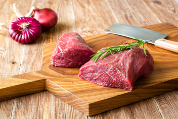 fresh raw meat on chopping board with onion. top-view