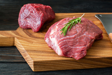 fresh raw meat on chopping board with rosemary