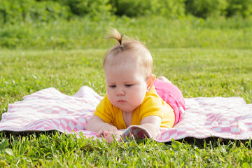 Little newborn girl lying on the grass