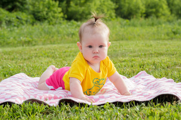 Little newborn girl lying on the grass