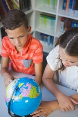 School kids studying globe in library