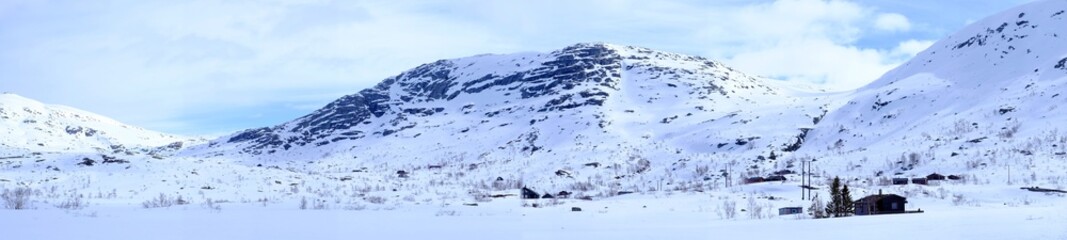 Fototapeta na wymiar Panorama of snow-capped mountains and huts