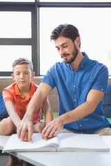 Teacher assisting blind student in library