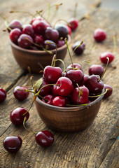 Ripe cherries in a clay bowl on a  wooden background