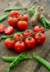 Fresh tomatoes with asparagus and green peas on a wooden backgro