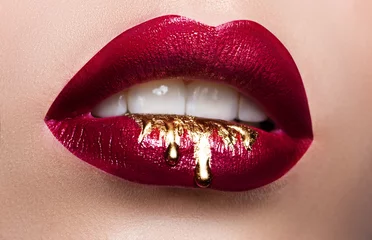 Schöne weibliche Lippennahaufnahme. Roter Lippenstift, goldene Farbe, die über seine Lippen fließt. Stock Foto kosmetische Werbung © akvafoto2012