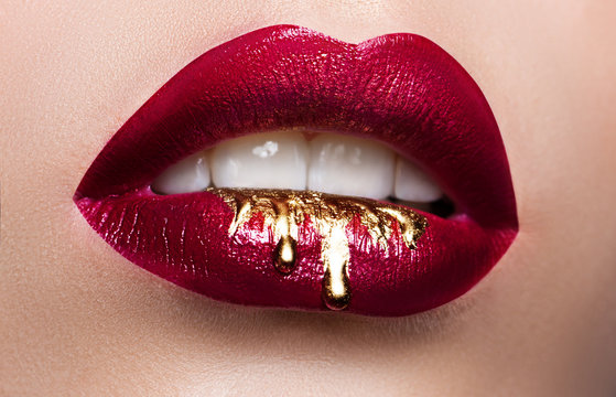 Beautiful female lips closeup. Red lipstick, gold paint flowing over his lips. Stock Photo Cosmetic Advertising