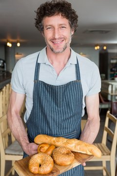 Waiter holding wooden tray with bread
